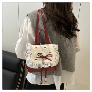 Detail of red bow, lace trim and heart pendant on a sweet vintage style backpack