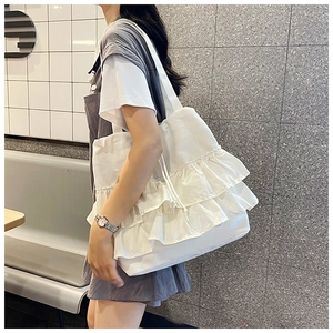 Detail of white pleated canvas tote bag with triple-layered ruffle design on model