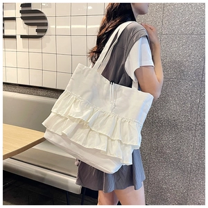 Detailed close-up of white pleated canvas tote bag with triple ruffle design on shoulder
