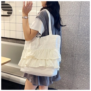Detail of white canvas tote bag with triple layered ruffles and drawstring closure
