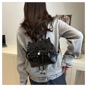 Close-up of black lace mini backpack featuring a bow, pearl pendant and ruffled edges