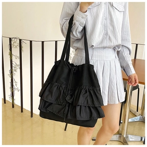 Detail of black ruffled tote bag with three-tier layered pleats and drawstring closure