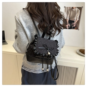 Close-up of black mini backpack featuring white lace trim, a delicate bow, and pearl charm