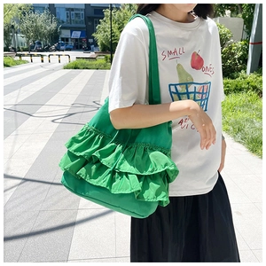 Detail of green pleated canvas tote bag with triple-layered ruffle design on wide shoulder strap