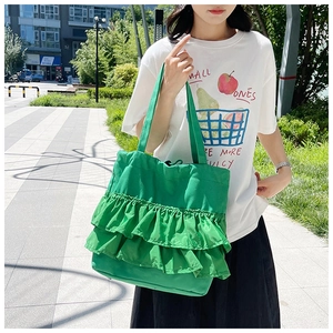 Outdoor shot of green ruffled canvas tote bag with layered pleats for casual summer style