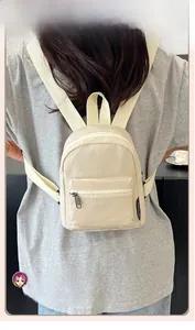 Detailed back view of a compact beige nylon mini backpack worn on a person
