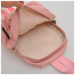 Detail view of pink nylon backpack interior with beige lining and branded woven label