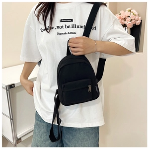 Mini black nylon backpack with adjustable straps shown on a model in a casual setting