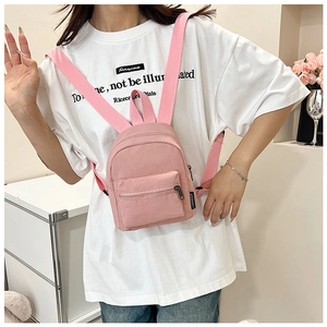 Front view of a pink mini nylon backpack with zipper pocket shown on a model
