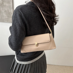 Minimalist beige glossy leather shoulder bag with gold metal buckle shown on a model