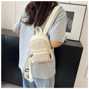 Cream white mini backpack shown as a versatile crossbody bag on a model in home setting