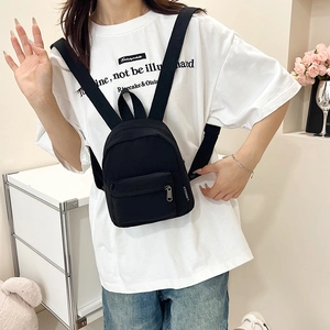 Minimalist black nylon mini backpack with a front pocket and stylish brand label