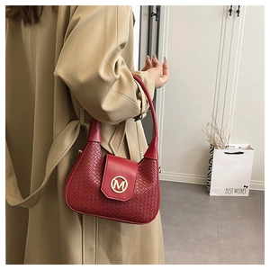 Detalle de bolso medialuna tejido rojo con hebilla M dorada y gabardina color beige
