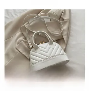 Detail of white quilted shell bag with gold hardware and phone for size reference