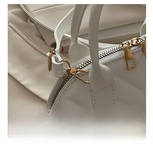 Macro shot of premium golden hardware and dual metal zippers on a white shell bag