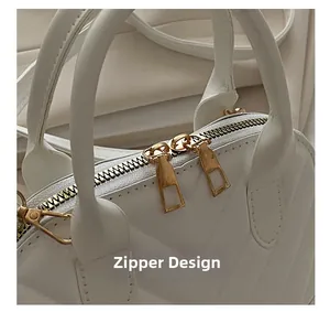 Close-up of golden dual-zipper closure on white shell bag with chevron quilting