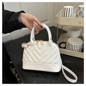 Detail of white quilted shell handbag with V-shaped texture and gold zipper hardware