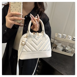 Detail of white V-quilted bowling bag with gold hardware and removable shoulder strap