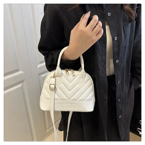 Detail of white chevron quilted shell bag with gold hardware and adjustable strap