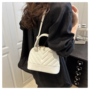 Detailed view of a white quilted shell bag with gold zipper and adjustable strap