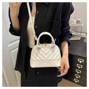 On-body view of white shell bag featuring V-shaped quilting and golden double zippers