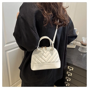 Rear view of a white quilted shell crossbody bag with a chic V-pattern and top handle
