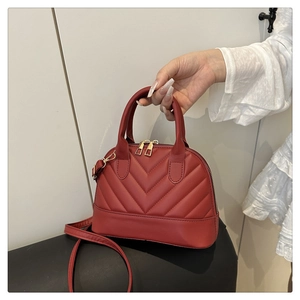 Detail of red shell-shaped bag with V-quilted stitching and polished gold hardware