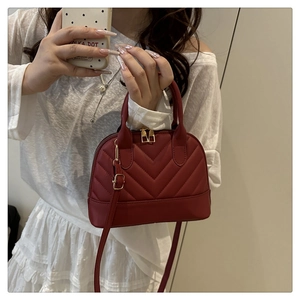 Macro view of burgundy shell bag featuring elegant V-shaped quilting and gold hardware