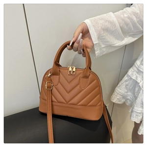Close-up of caramel shell bag with V-shaped quilting and golden zipper details