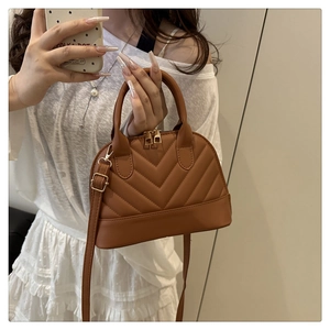 Detail of caramel brown shell bag with elegant V-shaped quilting and gold zippers