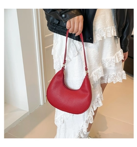 Close-up of red lychee textured crescent bag with elegant gold metal hardware detail