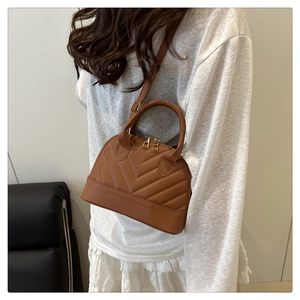 Detail of caramel striped shell bag with quilted V-stitching and gold double zippers