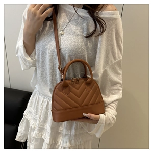 Detail of brown quilted shell bag with V-shaped stitching and adjustable strap