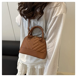 Detailed view of a brown quilted shell bag with V-shaped stitching and crossbody strap