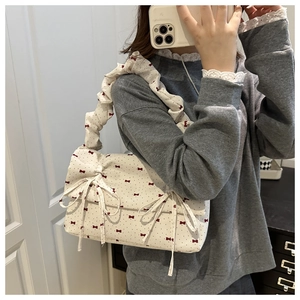 Detailed view of cream floral canvas bag featuring red bow prints and ruffled strap