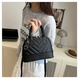 Detail of black shell bag featuring V-quilted faux leather and golden zipper closure