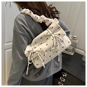 Detail of a chic cream shoulder bag with red bow prints and ruffled wide strap