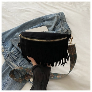 Close-up of black fringe crossbody bag with bohemian patterned strap and gold zipper