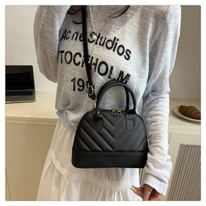 Detail showing classic black quilted shell handbag with elegant V-pattern stitching and strap