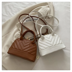Detail of white and brown chevron quilted dome bags on a beige blazer background