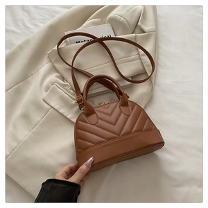 Detailed close-up of brown shell bag with V-shaped stitching and top handles