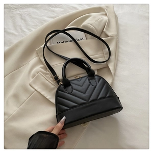 Close-up of black V-quilted faux leather shell bag with elegant gold hardware