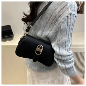 Detail einer schwarzen Satteltasche mit goldener Metallschnalle und verstellbarem Gurt