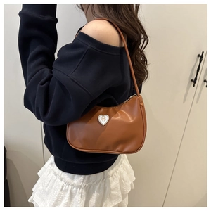 Brown half-moon underarm bag featuring a white heart with golden edges and bow detail