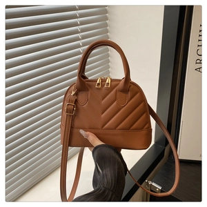 Detail of caramel quilted shell bag with gold hardware and adjustable strap