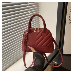 Detail of deep red shell bag with chevron quilting and golden hardware zipper