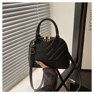 Close-up of black quilted shell bag with V-shaped stitching and gold-tone zippers
