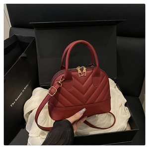 Deep burgundy quilted shell bag with gold hardware presented in a luxury gift box