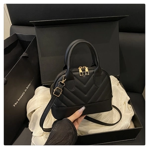 Detail of a black quilted shell handbag featuring gold zippers and an adjustable strap