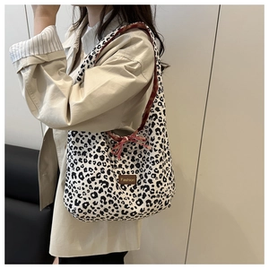Detail of leopard print tote bag with brown fashion tag and red contrast shoulder strap